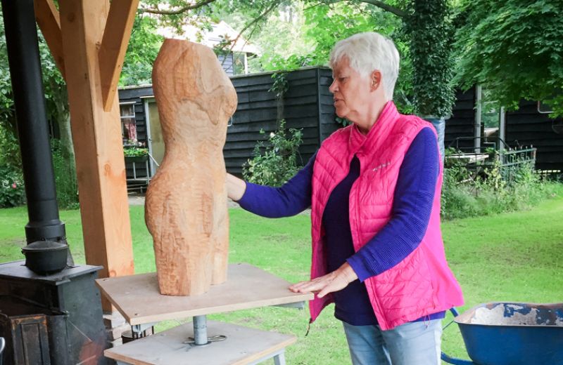Ina Vader aan het werk aan een houten beeld